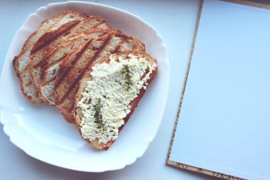 Bir somundan sandviçler ve ahşap bir stantta ve beyaz bir tabakta peynir ezmesi.