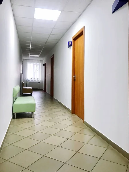 the window at the end of the corridor of the medical hospital center and the chairs from the door.