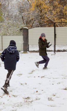 İki çocuk karda kartopu oynarken eğleniyor.