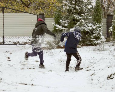 İki çocuk karda kartopu oynarken eğleniyor.