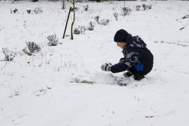 İki çocuk karda kartopu oynarken eğleniyor.