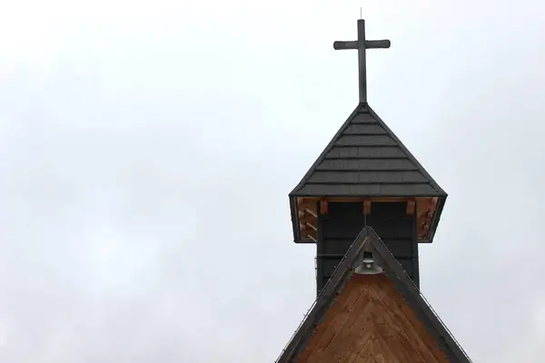 The top of the church with a cross against the background of a cloudy sky. High quality photo