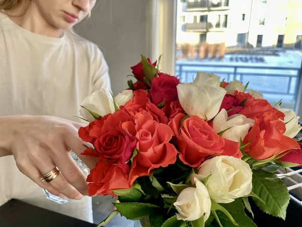 A young woman makes a bouquet of red roses