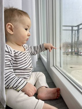 Pencereden bakan küçük şirin çocuk anne ve babasını bekliyor.