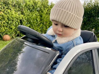 Küçük bir çocuk büyük beyaz bir çocuk arabasına biniyor.