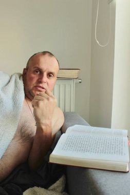 Orta yaşlı bir adam kitap okur ve kollarını sallayarak duygusal olarak anlatır ve açıklar.