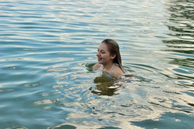 Kız nehirde yıkanır ve yüzmekten zevk alır.