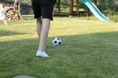 Bir genç, yeşil çimlerin üzerinde beyaz çoraplarla, yalın ayakla top oynuyor..