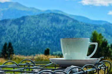 Beyaz fincanda sabah kahvesi ya da çay tabağında mavi renkli dağların arkasında. Yüksek kalite fotoğraf
