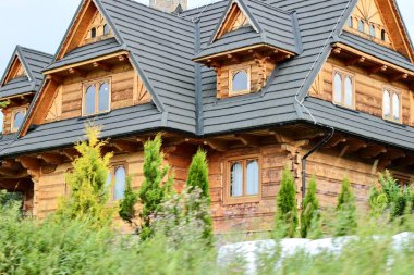 Polonya, Zakopane, 28 Temmuz 2024. Karmaşık çatı yapısı olan üç katlı ahşap bej bir ev. Yüksek kalite fotoğraf