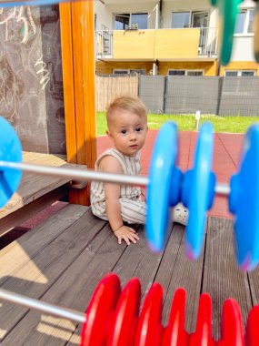 Çocuk yorgun bir şekilde abaküsün yanında oturuyor oyun parkında.