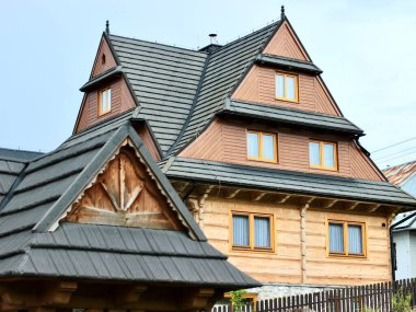 Polonya, Zakopane, 28 Temmuz 2024. Karmaşık çatı yapısı olan üç katlı ahşap bej bir ev. Yüksek kalite fotoğraf