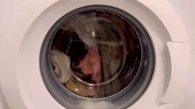 Kirli giysiler çamaşır makinesinin varilinde dönerek yıkanır.