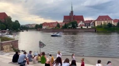 Polonya, Wroclaw, 12 Eylül 2024. İnsanlar Tumski Adası 'ndaki Odra Nehri üzerinde dinleniyor, katedralin manzarası....