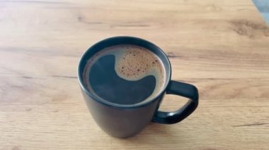 Kahverengi masada, siyah fincanda, ahşap yüzeyi olan bir sabah kahvesi.