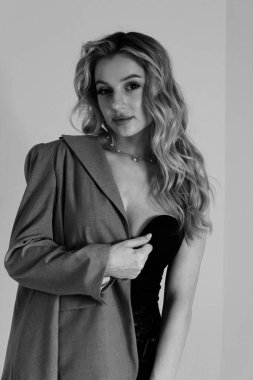Fotoğraf stüdyosunda poz veren seksi güzel kız modeli. Güzel, ince, ceketli bir sarışının siyah beyaz portresi.