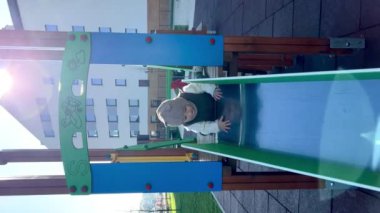 Küçük bir çocuk oyun parkında kaydırağa tırmanır..