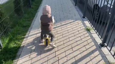 Bir çocuk mobilete biniyor. Küçük bir çocuk, sıcacık giyinmiş, yol boyunca bir kros bisikleti sürüyor.