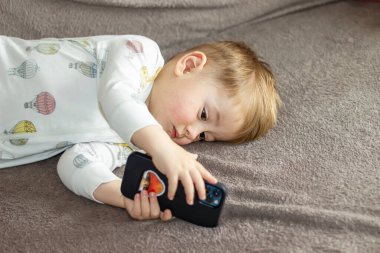 Akıllı telefonuyla oynayan küçük bir çocuk.