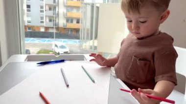 Bir buçuk yaşındaki bir çocuk hevesle çocuk masasında oynuyor, çocuk yazmayı ve çizmeyi öğreniyor..