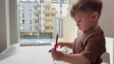 Bir buçuk yaşındaki bir çocuk hevesle çocuk masasında oynuyor, çocuk yazmayı ve çizmeyi öğreniyor..