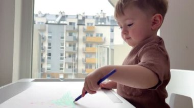 Bir buçuk yaşındaki bir çocuk hevesle çocuk masasında oynuyor, çocuk yazmayı ve çizmeyi öğreniyor..