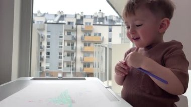 Bir buçuk yaşındaki bir çocuk hevesle çocuk masasında oynuyor, çocuk yazmayı ve çizmeyi öğreniyor..