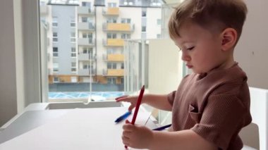 Bir buçuk yaşındaki bir çocuk hevesle çocuk masasında oynuyor, çocuk yazmayı ve çizmeyi öğreniyor..