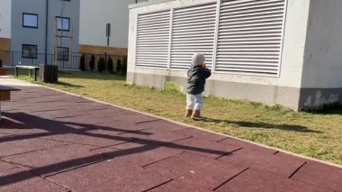 Küçük bir çocuk oyun sahasında topla oynuyor.