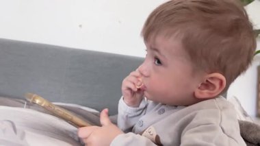 Küçük bir çocuk yemek çiğner ve telefona bakar.