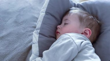 Küçük bir çocuk yastıkta uyuyor, uykulu bir bebek sallanıyor..