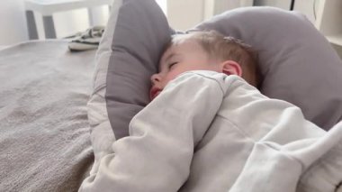 Küçük bir çocuk yastıkta uyuyor, uykulu bir bebek sallanıyor..