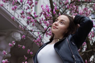 Pembe manolya çiçeklerinin altında kahverengi gözlü güzel bir esmer kadının portresi.