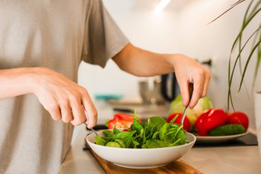 Bir adam vejetaryen sebze salatasını salata ve taze sebzelerle karıştırıyor. Yüksek kalite fotoğraf