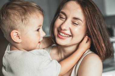 Mutlu, neşeli bir anne çocuğunu kucağında tutuyor, aile zamanının tadını çıkarıyor ve sevgi ve neşe ifade ediyor. Yüksek kalite fotoğraf