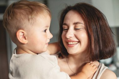 Mutlu, neşeli bir anne çocuğunu kucağında tutuyor, aile zamanının tadını çıkarıyor ve sevgi ve neşe ifade ediyor. Yüksek kalite fotoğraf
