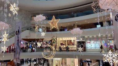 Polonya, Wroclaw, 12.12.2024. Noel tatilinden önce süslü bir alışveriş merkezi galerisi. Alışveriş yapanlar Noel ışıkları ve Noel süsleriyle modern bir ticaret merkezinde yürüyüp hediyeler alıyorlar. Tatil hazırlıklarının mevsimsel atmosferi.