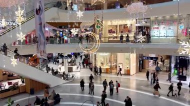 Polonya, Wroclaw, 12.12.2024. Noel tatilinden önce süslü bir alışveriş merkezi galerisi. Alışveriş yapanlar Noel ışıkları ve Noel süsleriyle modern bir ticaret merkezinde yürüyüp hediyeler alıyorlar. Tatil hazırlıklarının mevsimsel atmosferi.