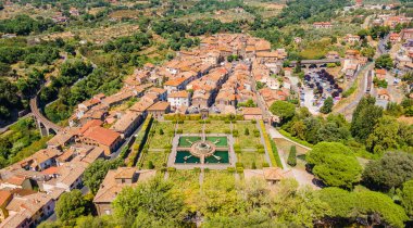 Kare parkı, demiryolu ve köprüsü olan küçük bir İtalyan kasabasının panoramik hava manzarası