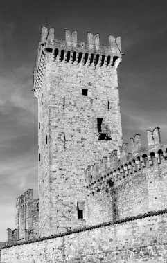 Ortaçağ şatosunun taş kulesi. Duvarın küçük bir kısmı bulutlarla kaplı. Siyah beyaz fotoğraf
