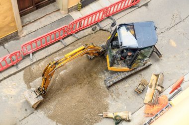 Küçük bir kazıcının dar bir caddedeki yol çalışması sürecindeki üst görüntüsü