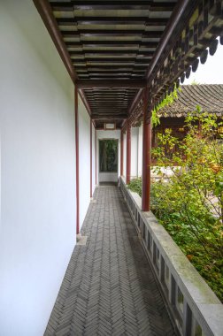 Bir tarafında beyaz bir duvar, diğer tarafında duvar olmayan uzun bir doğu galerisi. Geometrik perspektif. Dikey gerçek fotoğraf