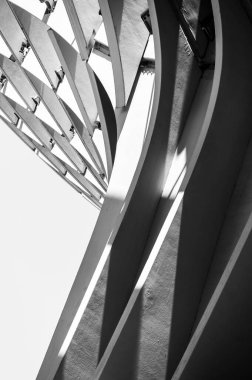 Metal eğri elementlerin, paralel çizgilerin, ışığın ve gölgenin bir kısmından geometrik soyutlama. Siyah ve beyaz dikey fotoğraf