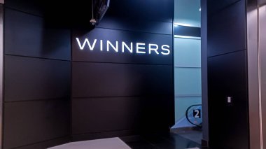 Toronto, ON, Canada - February 26, 2024: View at the brand identity sign over the entrance of a Winners discount fashion store in a shopping mall in Toronto clipart