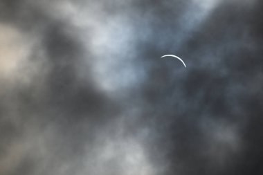 Toronto, ON, Canada - April 8, 2024: Partial solar eclipse 2024 seen from a cloudy sky near Toronto in Canada clipart