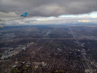 Toronto, Kanada 26 Kasım 2024: Toronto banliyölerinin hava görüntüsü dramatik bulutlar altında bir Air Transat uçağı kalkıştan sonra yükseliyor..