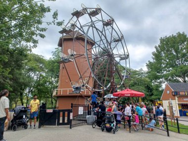 Toronto, ON, Kanada 08 Ağustos 2024: Aileler güneşli bir yaz gününde Centerville Lunaparkı 'nda klasik dönme dolaba binmek için sıraya girerler..