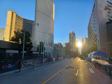 Toronto, ON, Kanada 19 Ekim 2024: Sabahın erken saatlerinde Toronto Waterfront Maratonu 'na hazırlanan yarış personeli olarak gökdelenlerden yansıyor. Toronto Belediye Binası 'nın yanındaki pistte bayraklar var...