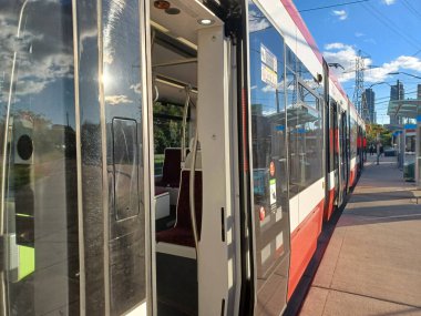 Toronto, ON, Kanada 19 Temmuz 2024: Modern bir TTC tramvayı, kapıları açık ve iç ışıkları parlayan virajlı bir durakta bekliyor..