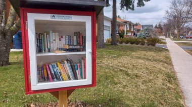 Toronto, ON, Kanada - 13 Nisan 2025: Bir yerleşim bölgesindeki kaldırım kenarında beyaz bir Serbest Kütüphane duruyor.